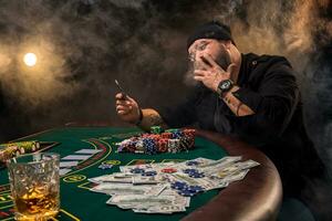 barbado hombre con cigarro y vaso sentado a póker mesa en un casino. juego, jugando tarjetas y ruleta. foto