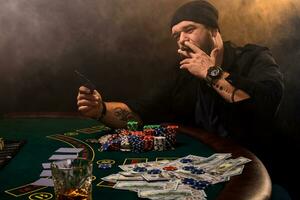 barbado hombre con cigarro y vaso sentado a póker mesa en un casino. juego, jugando tarjetas y ruleta. foto