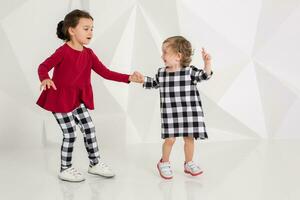 Children sisters play together on white background photo