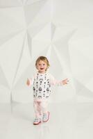 Year-old child standing near white wall in studio photo