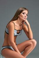 Beautiful girl in sports underwear isolated on gray background photo