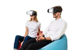 Excited young couple experiencing virtual reality seated on beanbags isolated on white background photo