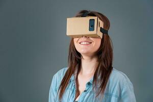 Woman using a new virtual reality headset on grey background photo