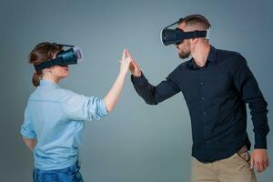 Young couple using VR headsets on grey background photo