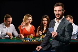 Poker players in casino with cards and chips on black background photo