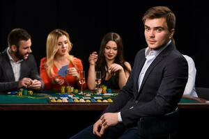 Poker players in casino with cards and chips on black background photo