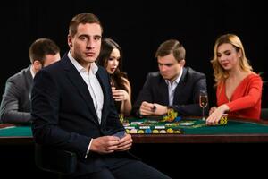 Young people playing poker at the table. Casino photo