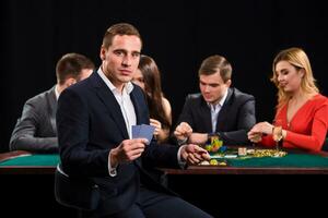 Poker players in casino with cards and chips on black background photo