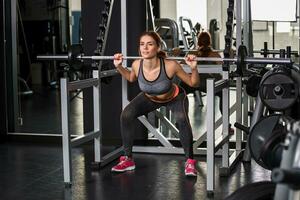 muscular joven mujer haciendo ejercicios en el simulador en el gimnasio foto