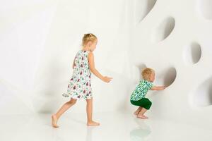 Brother and sister playing and smiling in a white studio photo