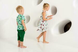 Brother and sister playing and smiling in a white studio photo