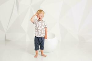 little boy in a t-shirt and shorts on a white background photo