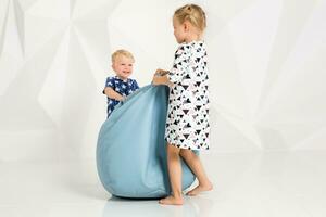 Brother and sister playing and smiling in a white studio photo