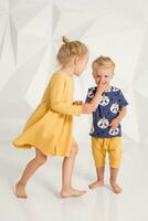 hermano y hermana jugando y sonriente en un blanco estudio foto