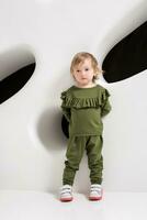 Year-old child standing near white wall in studio photo