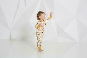 Year-old child standing near white wall in studio photo