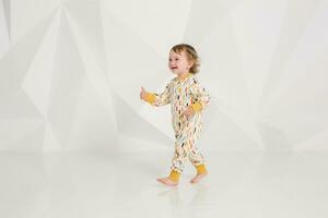 Year-old child standing near white wall in studio photo