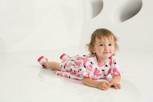 Smiling little girl sitting on the floor on a white background photo