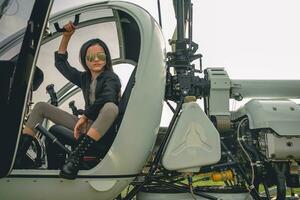 Brunette tweenager in mirrored sunglasses sitting in open helicopter cockpit photo