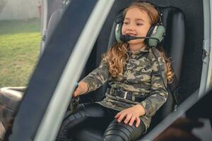 Cheerful tween girl in headset sitting on pilot seat in helicopter photo