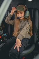 Interested preteen girl in headset sitting on pilot seat in helicopter photo