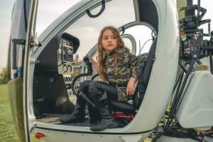 preadolescente niña vistiendo camuflaje estilo vestir sentado en abierto helicóptero foto