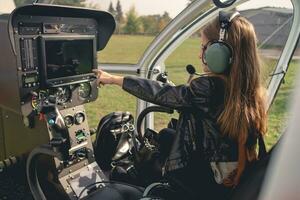 Preteen girl in headset pointing at dashboard in helicopter cockpit photo