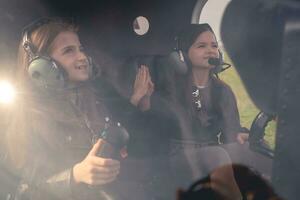 dos preadolescente muchachas en auriculares sentado en helicóptero dando alto cinco foto