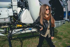 Confident tween girl in sunglasses standing near open helicopter photo