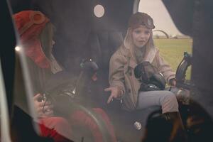 Surprised tween girl sitting on pilot seat in helicopter cockpit with friend photo