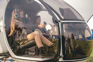 Excited tween girl in aviator headphones sitting in helicopter cockpit photo