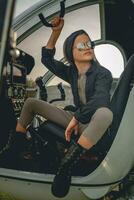 Tween girl in mirrored sunglasses sitting on pilots seat in open helicopter photo