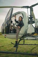 Confident preteen girl in mirrored sunglasses standing on footboard of helicopter photo