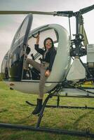 Smiling tween girl in mirrored sunglasses standing on footboard of helicopter photo