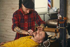 Client during beard shaving in barber shop photo