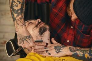 Client during beard shaving in barber shop photo