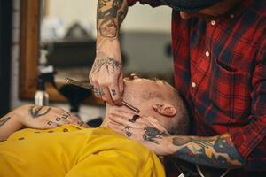 Client during beard shaving in barber shop photo