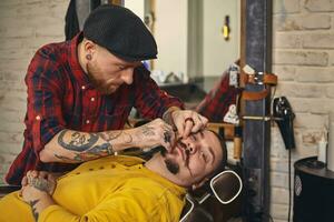 Client during beard shaving in barber shop photo