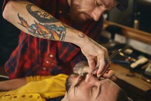 Client during beard shaving in barber shop photo