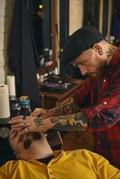 Client during beard shaving in barber shop photo