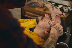 Client during beard shaving in barber shop photo