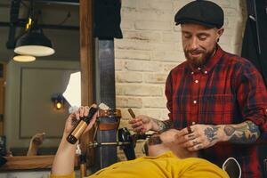 Client during beard shaving in barber shop photo