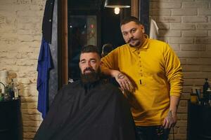 Client with big black beard during beard shaving in barber shop photo