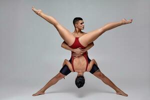 The couple of an athletic modern ballet dancers are posing against a gray studio background. photo