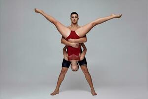 The couple of an athletic modern ballet dancers are posing against a gray studio background. photo