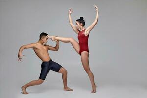 The couple of an athletic modern ballet dancers are posing against a gray studio background. photo