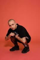 Studio shot of a young tattoed bald man posing against a pink background. 90s style. photo