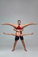 The couple of an athletic modern ballet dancers are posing against a gray studio background. photo