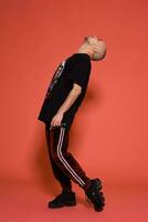 Studio shot of a young tattoed bald man posing against a pink background. 90s style. photo