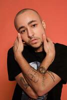 Studio shot of a young tattoed bald man posing against a pink background. 90s style. photo